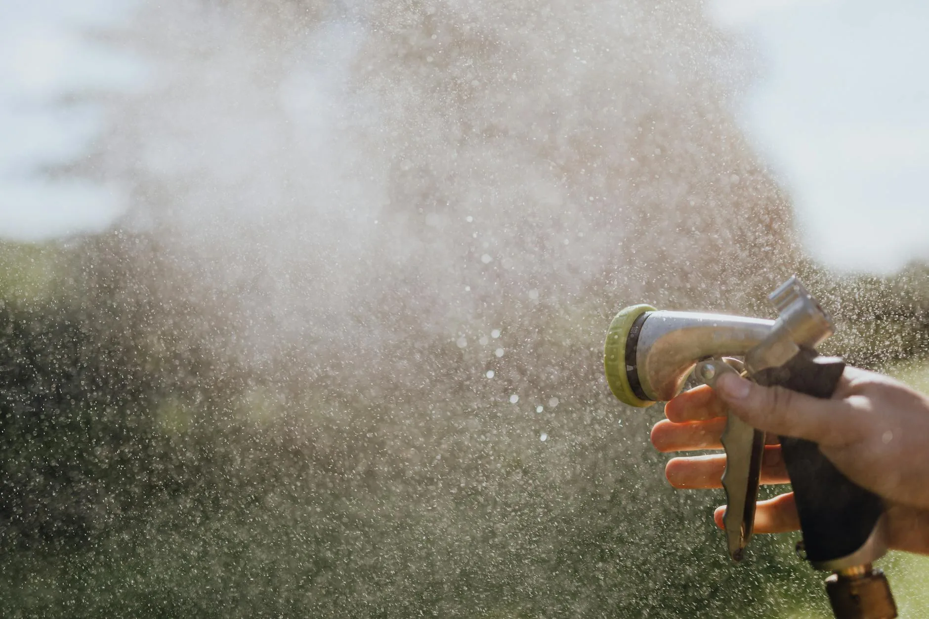 Garden hose nozzle spraying water outdoors