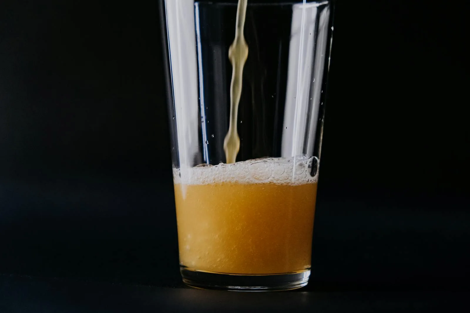 Freshly brewed homebrew beer being poured into a glass with foamy head