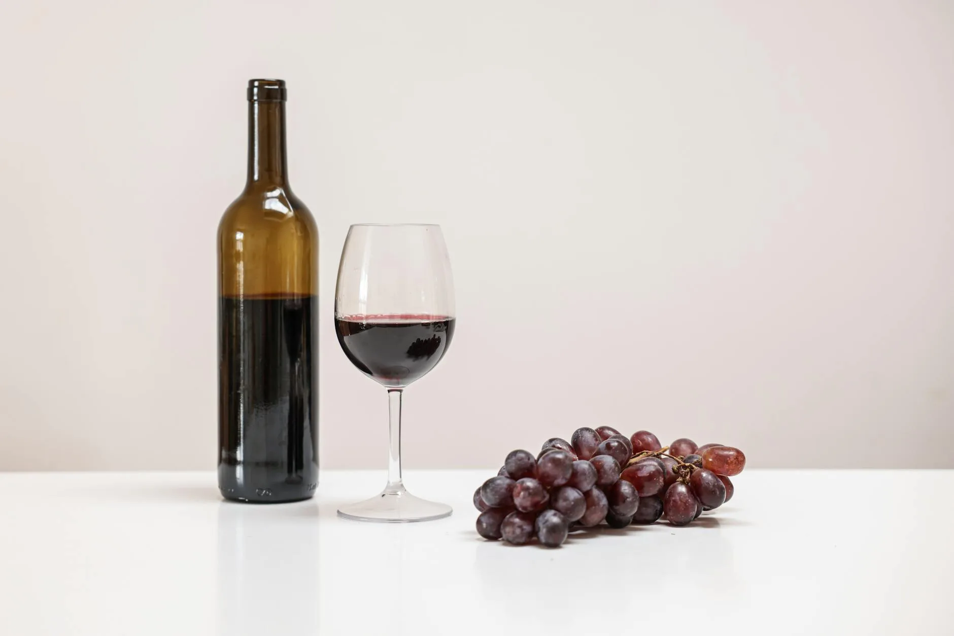 Glass of homemade red wine next to a bottle
