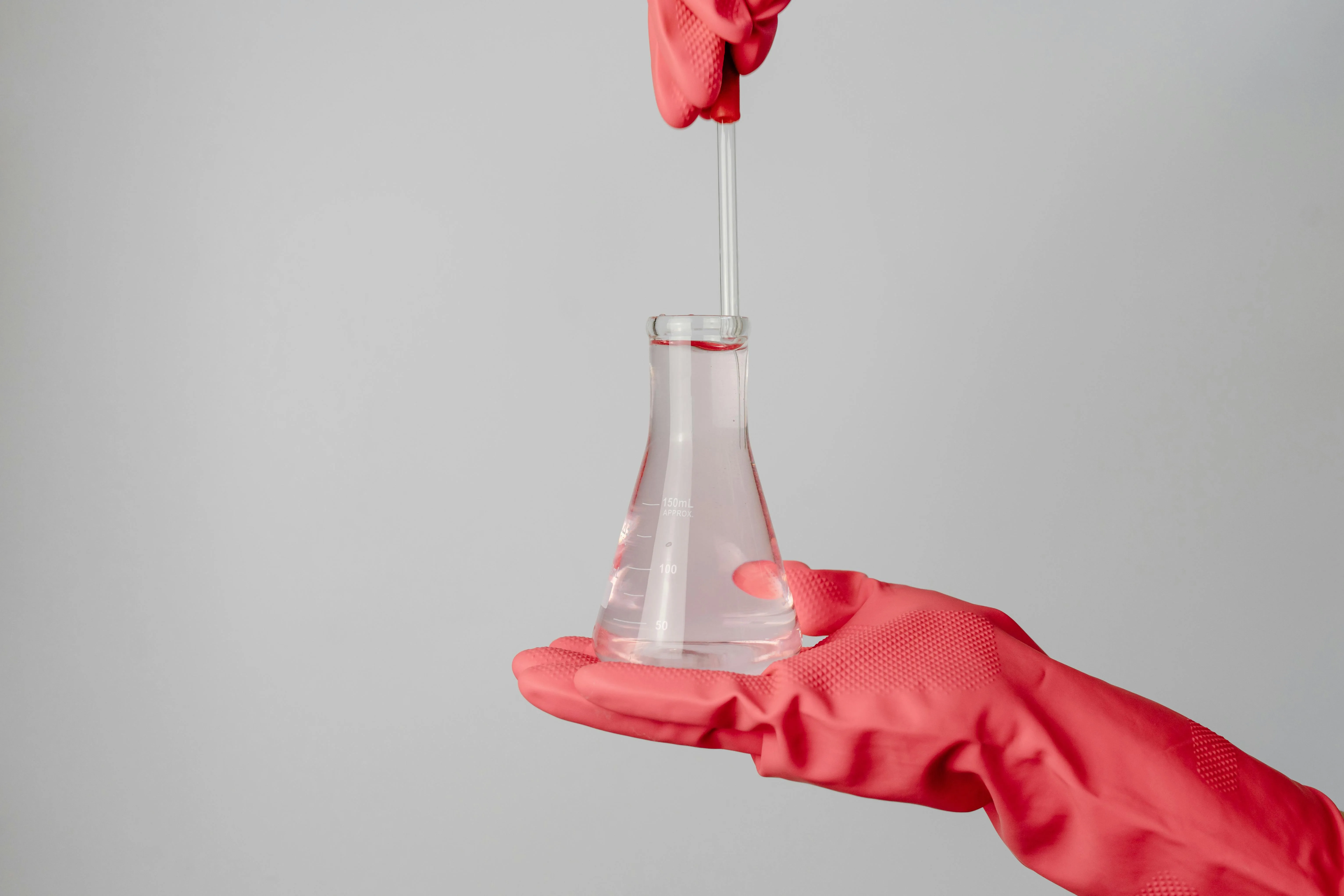 Gloved hand holding a flask of water for pH and mineral testing
