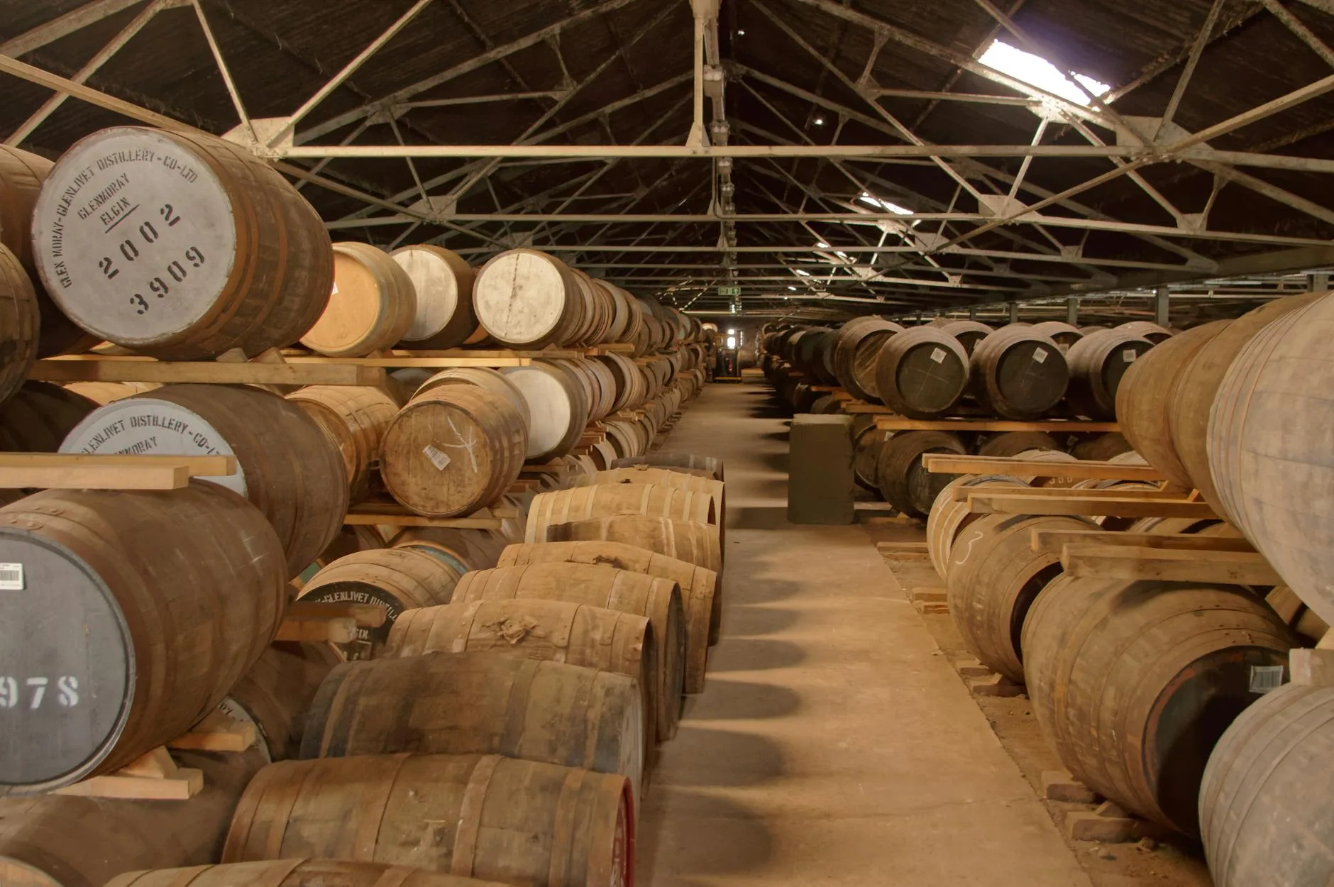 Whisky in a glass next to a small oak ageing barrel